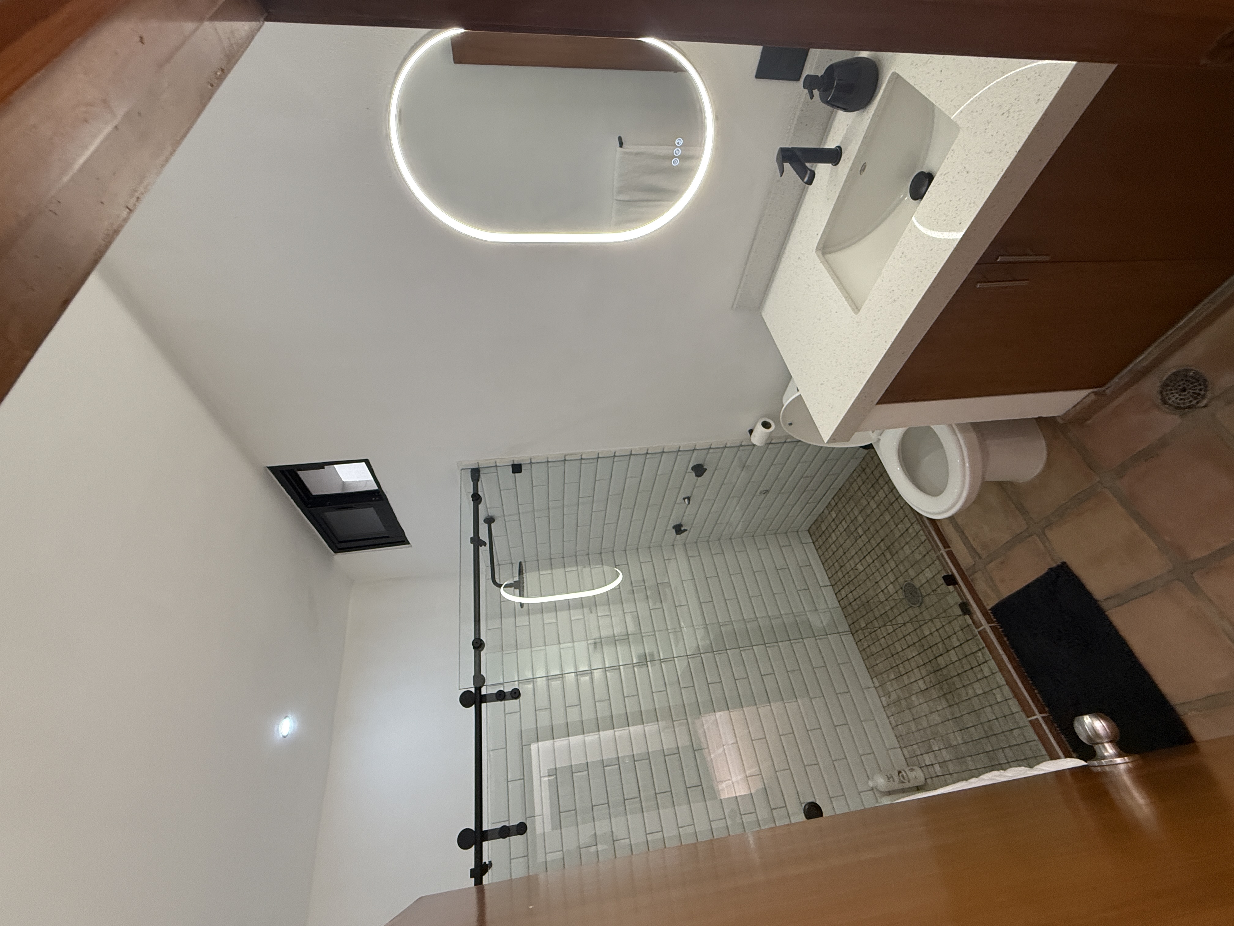 Downstairs bathroom with glass-enclosed shower, white tile and illuminated mirror